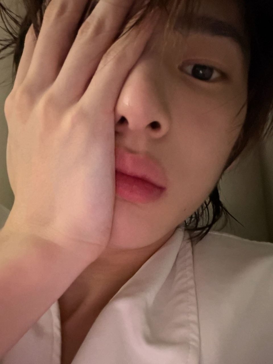 Amane in a white shirt with his hand beside his face