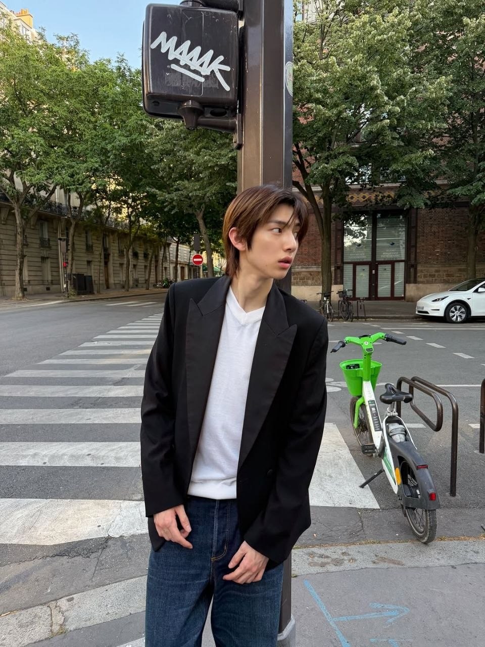 Amane in a black jacket at a street crossing